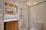 This charming bathroom features a wooden vanity with a white sink and a large mirror with built-in lighting.