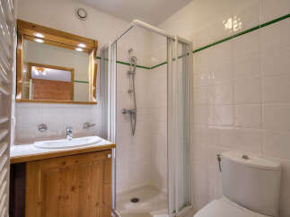 This charming bathroom features a wooden vanity with a white sink and a large mirror with built-in lighting.