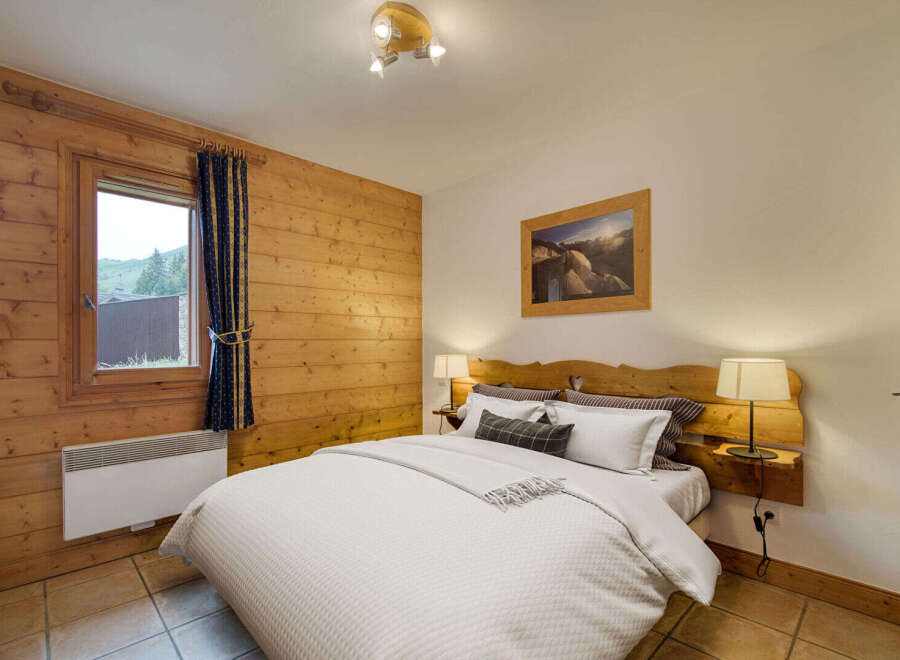 Experience cozy mountain living in this charming bedroom, featuring warm wood paneling and a comfortable queen-sized bed.