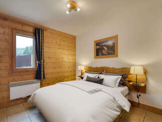 Experience cozy mountain living in this charming bedroom, featuring warm wood paneling and a comfortable queen-sized bed.