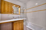 This charming bathroom features a wooden vanity with ample storage and a built-in mirror with integrated lighting.