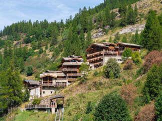 Discover this stunning alpine retreat nestled on a lush mountainside, featuring traditional wooden chalets with multiple balconies offering breathtaking views.
