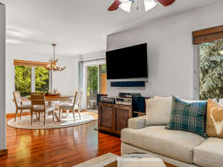 This inviting living and dining area features a stylish antler chandelier illuminating a round dining table with four chairs.