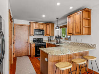 Discover this charming kitchen featuring warm wooden cabinetry and a granite countertop island perfect for casual dining.
