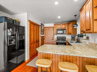 Discover this charming kitchen featuring warm wooden cabinetry and a granite-topped island perfect for casual dining.