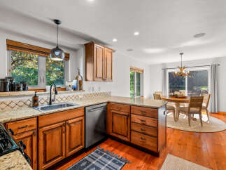 This spacious kitchen features warm wooden cabinetry, granite countertops, and a large window overlooking lush greenery.