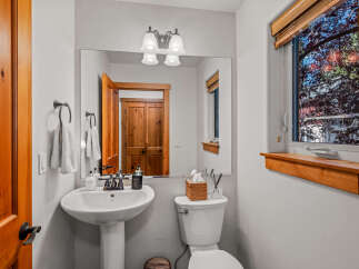 This charming bathroom features a classic pedestal sink with a bronze faucet, complemented by a large vanity mirror and elegant light fixtures.