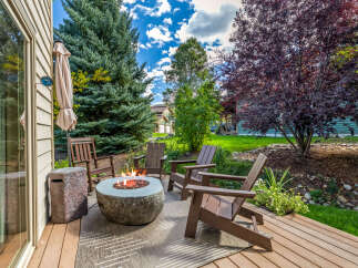 Enjoy outdoor living with this inviting patio featuring a stone fire pit and comfortable Adirondack chairs, perfect for gathering with friends and family.