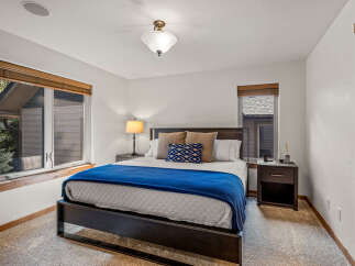 Experience comfort and style in this inviting bedroom, featuring a plush bed adorned with a vibrant blue throw and decorative pillows.