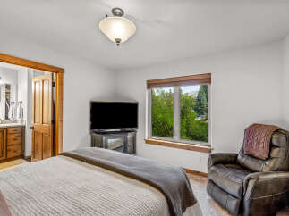 This cozy bedroom features a comfortable bed, a large flat-screen TV, and a plush recliner perfect for relaxing.