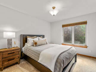 This cozy bedroom features a comfortable queen-size bed with striped bedding and plush pillows, perfect for a restful night's sleep.