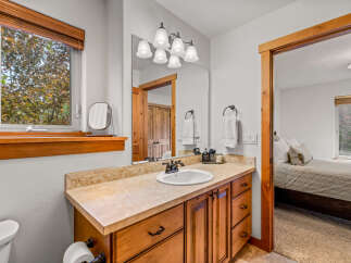 This charming bathroom features a spacious wooden vanity with a granite countertop and a white undermount sink, complemented by a large mirror and elegant light fixtures.