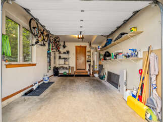 This spacious garage offers ample storage solutions, including overhead bike racks and wall-mounted shelves, perfect for organizing your gear.