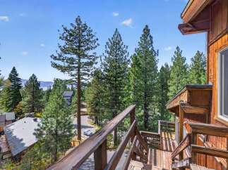 Experience breathtaking lake and mountain views from this charming wooden home, nestled amidst towering pine trees.