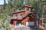 Nestled amidst tall pine trees, this multi-level wooden home offers a unique architectural design with expansive decks and an inviting exterior.