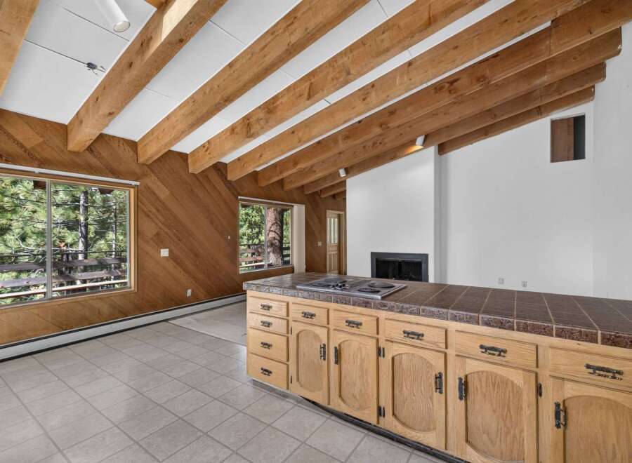 Experience rustic charm in this spacious living area featuring a vaulted ceiling with exposed wooden beams and a cozy fireplace.