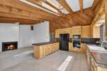Experience rustic charm in this spacious kitchen featuring warm wooden beams and a vaulted ceiling with a skylight.