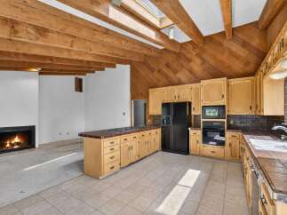 Experience rustic charm in this spacious kitchen featuring warm wooden beams and a vaulted ceiling with a skylight.