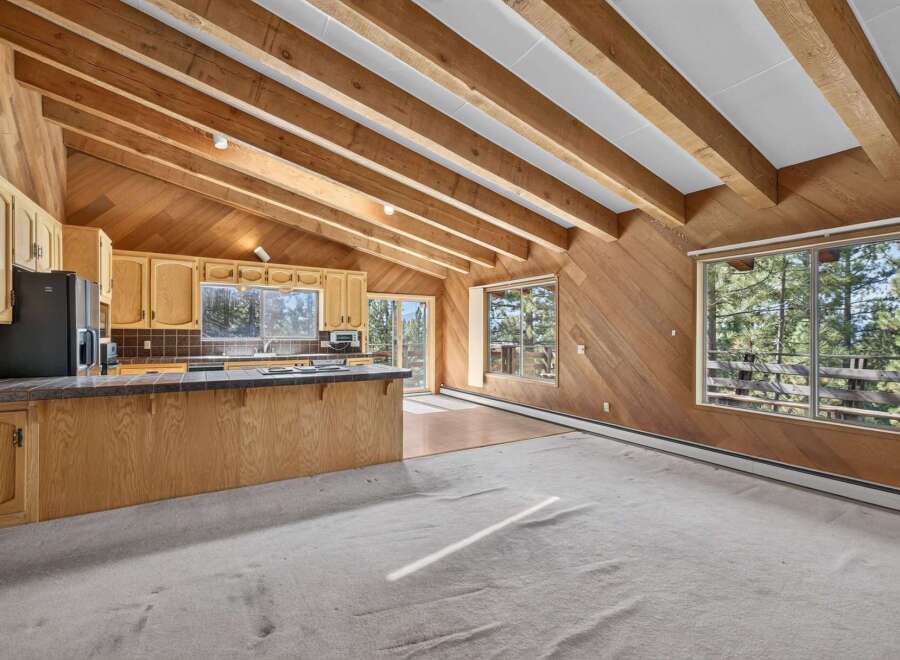 Experience rustic charm in this open-concept living space featuring a vaulted wood-beamed ceiling and abundant natural light.