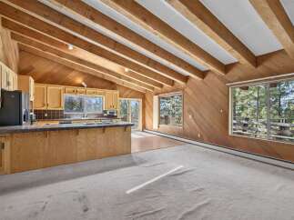 Experience rustic charm in this open-concept living space featuring a vaulted wood-beamed ceiling and abundant natural light.