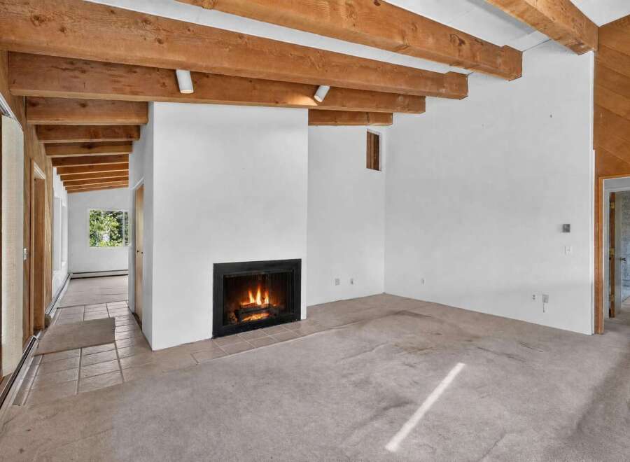 Experience rustic charm in this spacious living area featuring exposed wooden beams and a cozy fireplace, perfect for gathering.