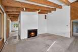 Experience rustic charm in this spacious living area featuring exposed wooden beams and a cozy fireplace, perfect for gathering.