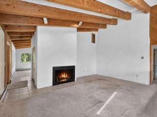 Experience rustic charm in this spacious living area featuring exposed wooden beams and a cozy fireplace, perfect for gathering.