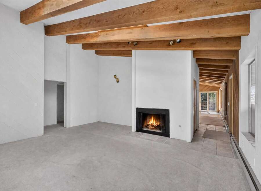 Experience rustic charm in this spacious living area featuring exposed wooden beams and a cozy fireplace, perfect for gathering with loved ones.