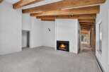 Experience rustic charm in this spacious living area featuring exposed wooden beams and a cozy fireplace, perfect for gathering with loved ones.