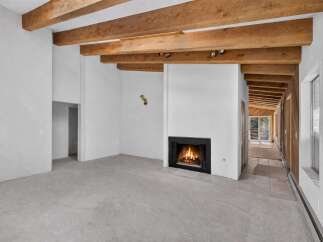 Experience rustic charm in this spacious living area featuring exposed wooden beams and a cozy fireplace, perfect for gathering with loved ones.