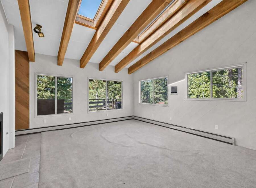 Experience the warmth of this inviting living space, featuring a cozy fireplace and a stunning vaulted ceiling with exposed wooden beams.