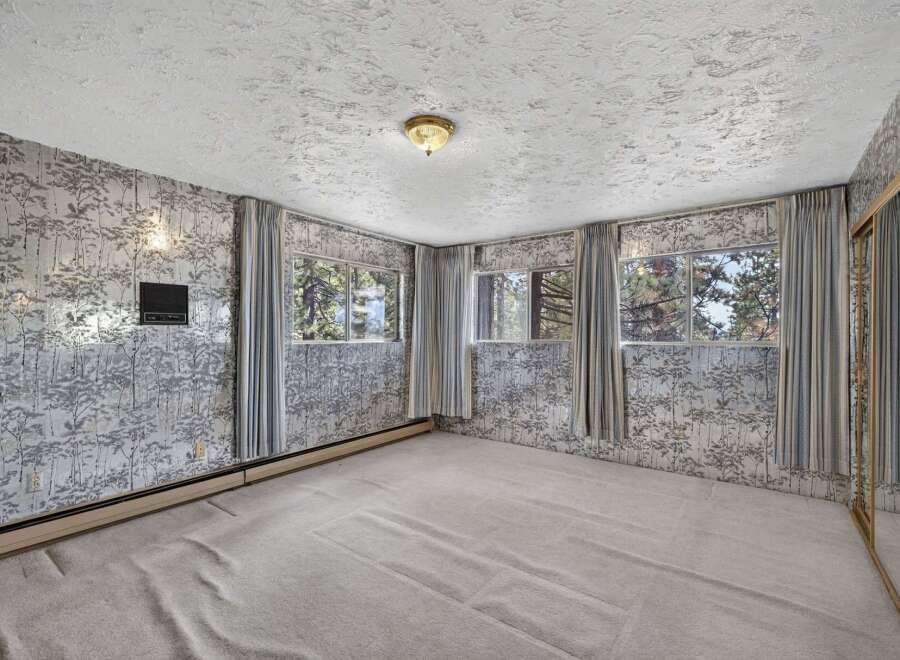 Step into this charming room featuring unique forest-themed wallpaper and large windows that offer picturesque views of the surrounding trees.