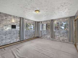 Step into this charming room featuring unique forest-themed wallpaper and large windows that offer picturesque views of the surrounding trees.