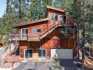 Nestled among tall pine trees, this rustic wooden home offers a unique mountain retreat.