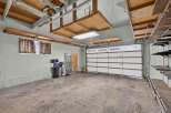 This spacious garage offers ample storage solutions with overhead wooden shelves and wall-mounted shelving units.
