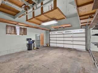 This spacious garage offers ample storage solutions with overhead wooden shelves and wall-mounted shelving units.
