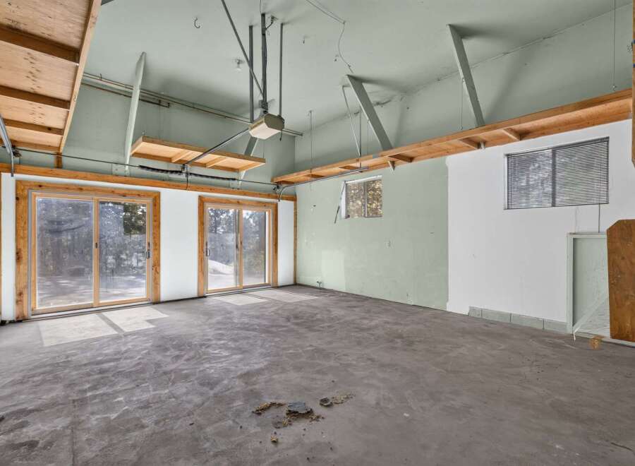 This spacious garage offers ample room for vehicles and storage, featuring large sliding glass doors that provide easy access and natural light.