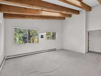 Experience the rustic charm of this spacious room, featuring exposed wooden beams that add warmth and character to the vaulted ceiling.