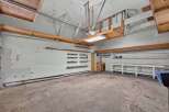 Discover ample storage and workspace in this spacious garage, featuring multiple shelves and a large workbench.
