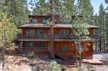 Nestled amidst towering pine trees, this multi-level wooden home offers a rustic retreat with ample outdoor living space.