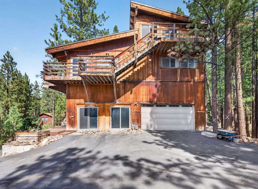 Nestled among tall pine trees, this rustic wooden home offers a unique architectural style with multiple levels and balconies.