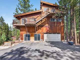 Nestled among tall pine trees, this rustic wooden home offers a unique architectural style with multiple levels and balconies.