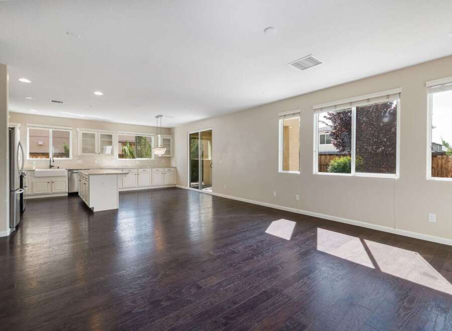 This spacious open-concept living area features a modern kitchen with ample cabinet space, a large island, and a farmhouse sink, perfect for entertaining.