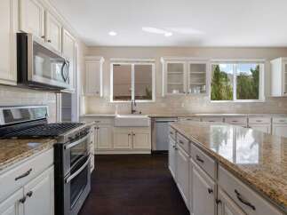 This spacious kitchen boasts elegant cream cabinetry complemented by a stunning granite-topped island, perfect for meal preparation and entertaining.