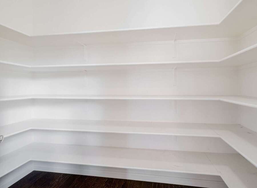 Discover ample storage in this spacious walk-in pantry, featuring multiple white shelves perfect for organizing all your kitchen essentials.