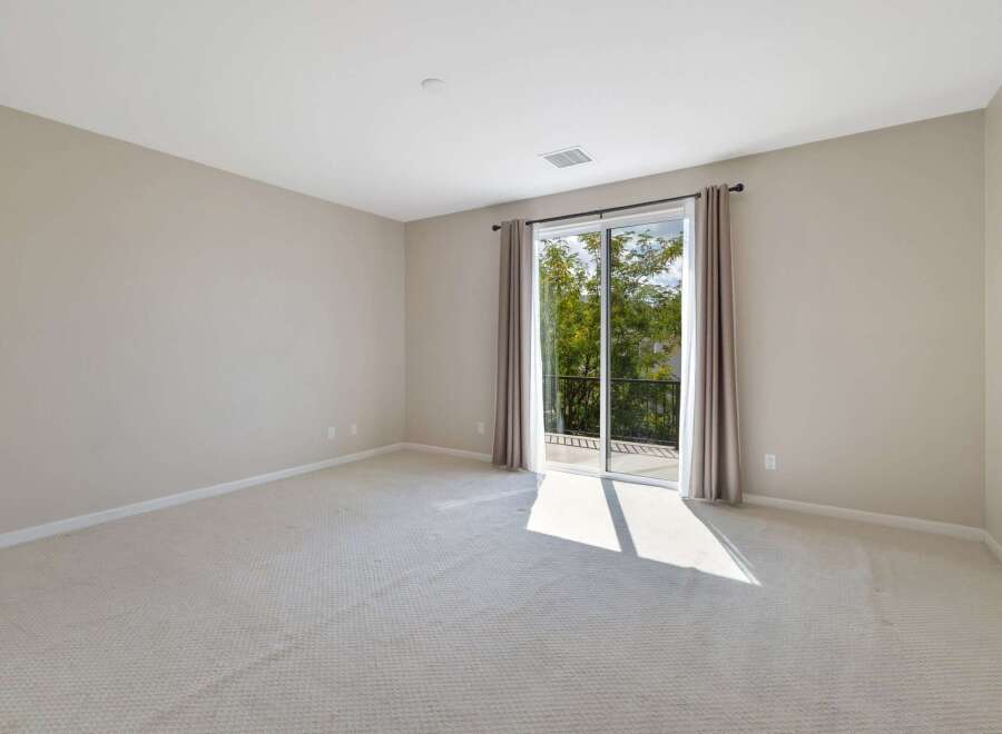 This spacious room features neutral carpeting and light beige walls, creating a serene and versatile atmosphere.