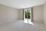 This spacious room features neutral carpeting and light beige walls, creating a serene and versatile atmosphere.