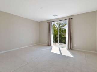 This spacious room features neutral carpeting and light beige walls, creating a serene and versatile atmosphere.