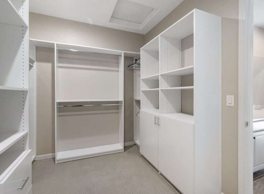 Discover ample storage in this spacious walk-in closet, featuring custom shelving and hanging rods to organize your wardrobe.