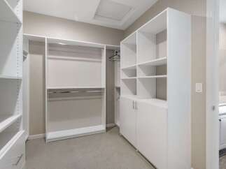 Discover ample storage in this spacious walk-in closet, featuring custom shelving and hanging rods to organize your wardrobe.